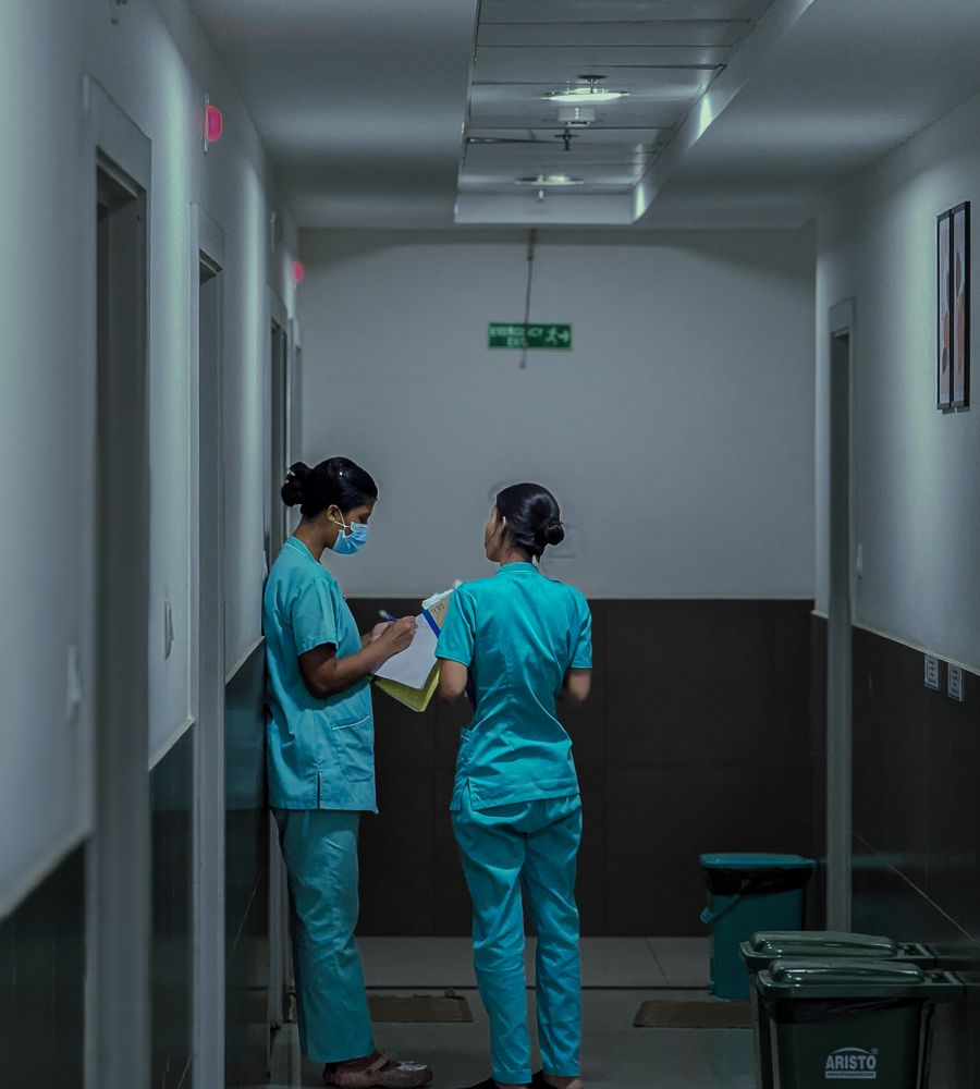 Nurses discussing patient notes in a hospital corridor
