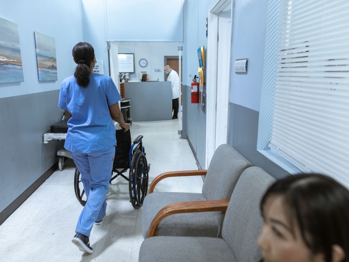 Nurse assisting a patient in a hospital hallway