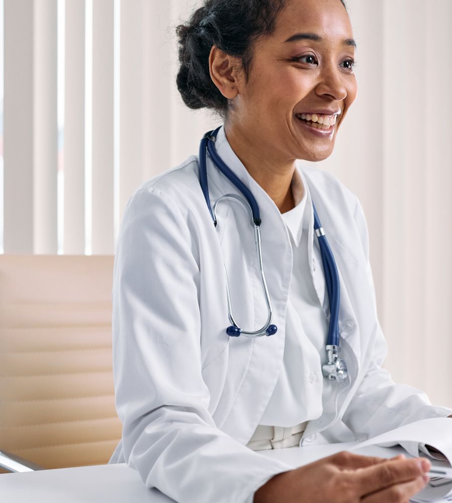 Physician smiling at her desk in a clinic